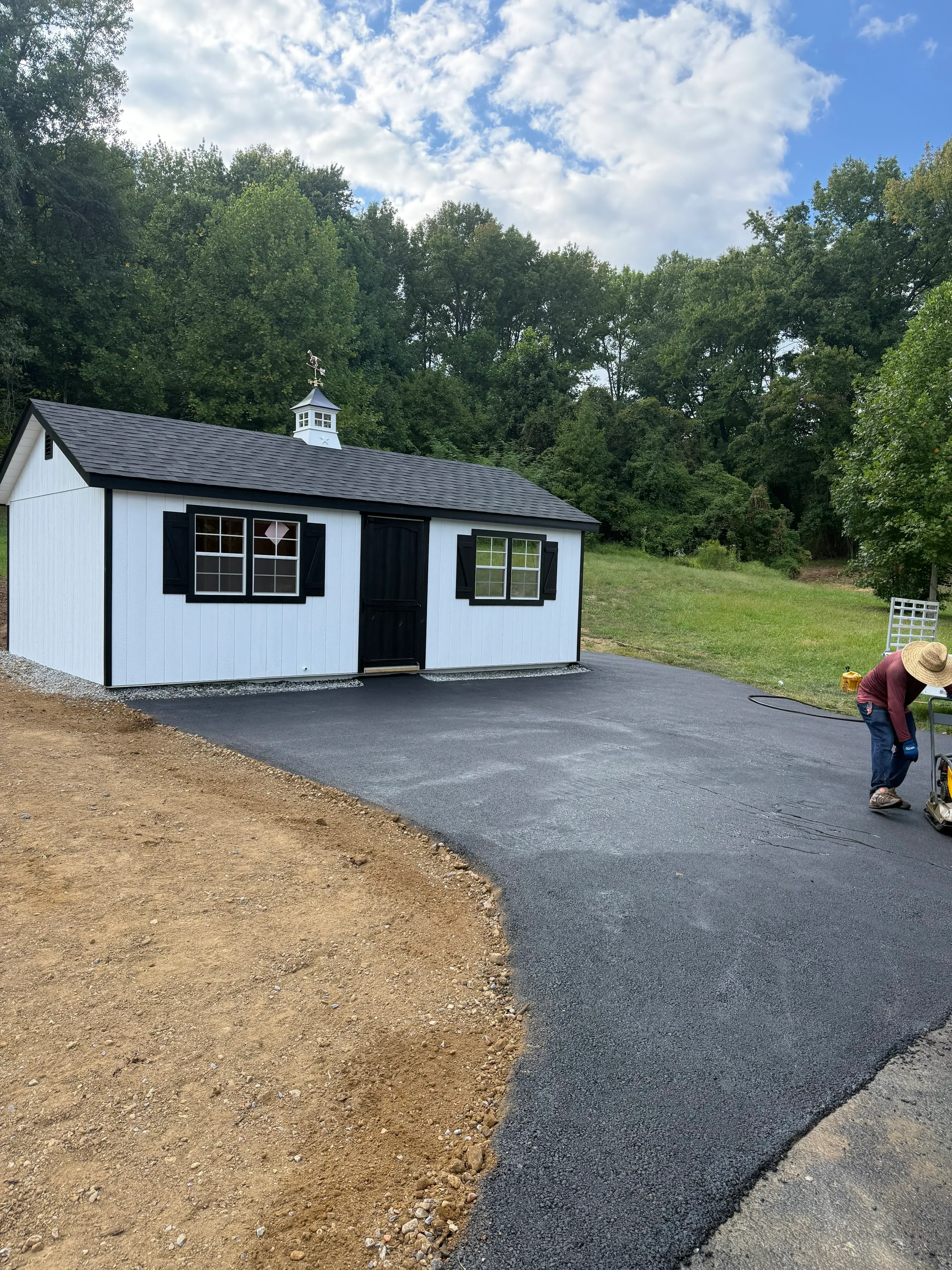 Newly installed black asphalt driveway with metal roof structure and prepared subbase