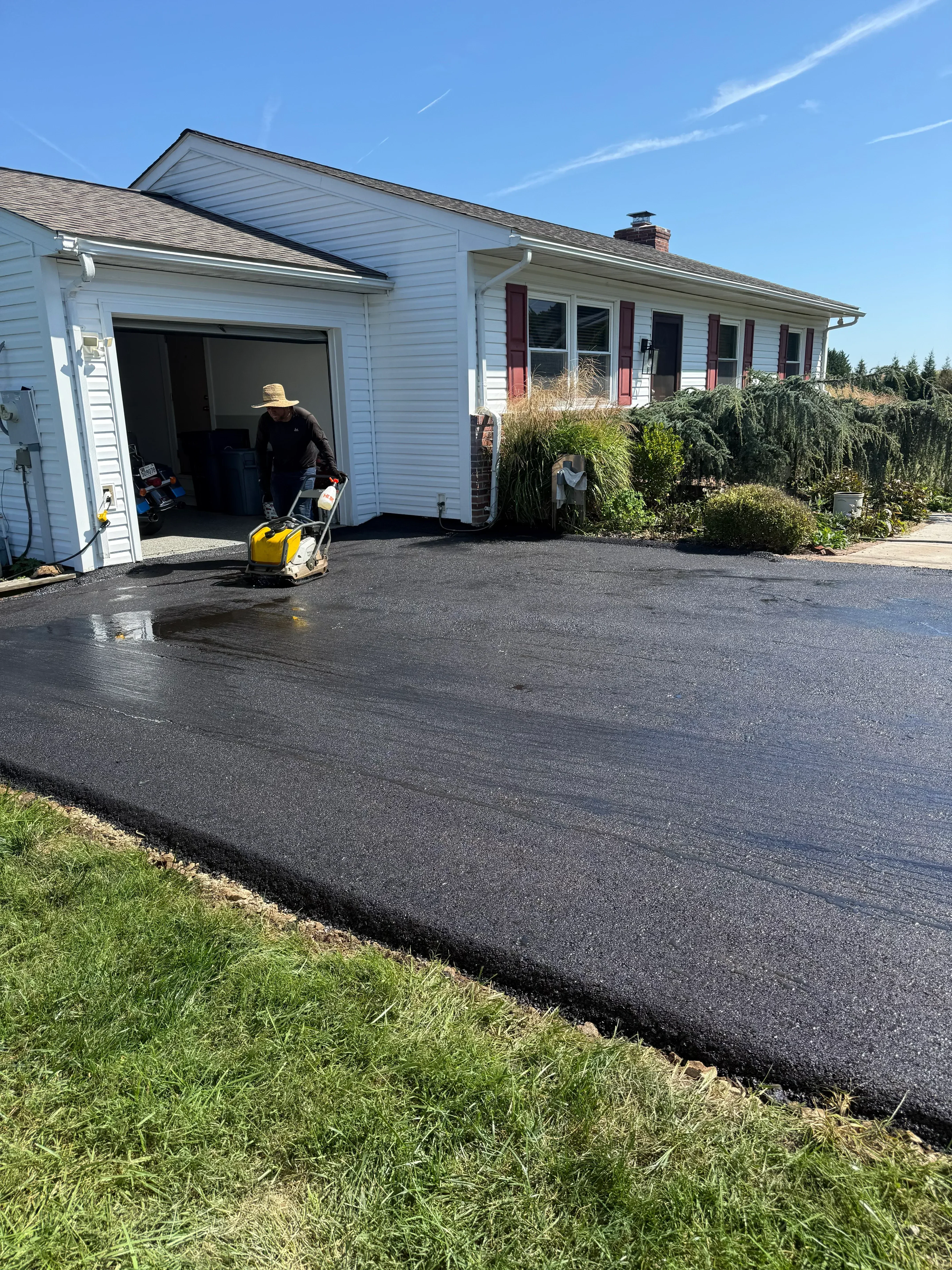 Newly installed dark asphalt driveway with clean edges at residential home entrance